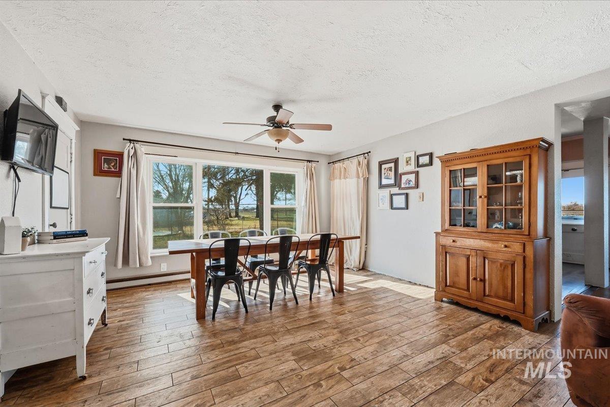 148 Glascock Road Weiser, ID 83672 - Photo 12 of 32 Dining room with a ceiling fan, light wood-style flooring, a textured ceiling, and a baseboard radiator