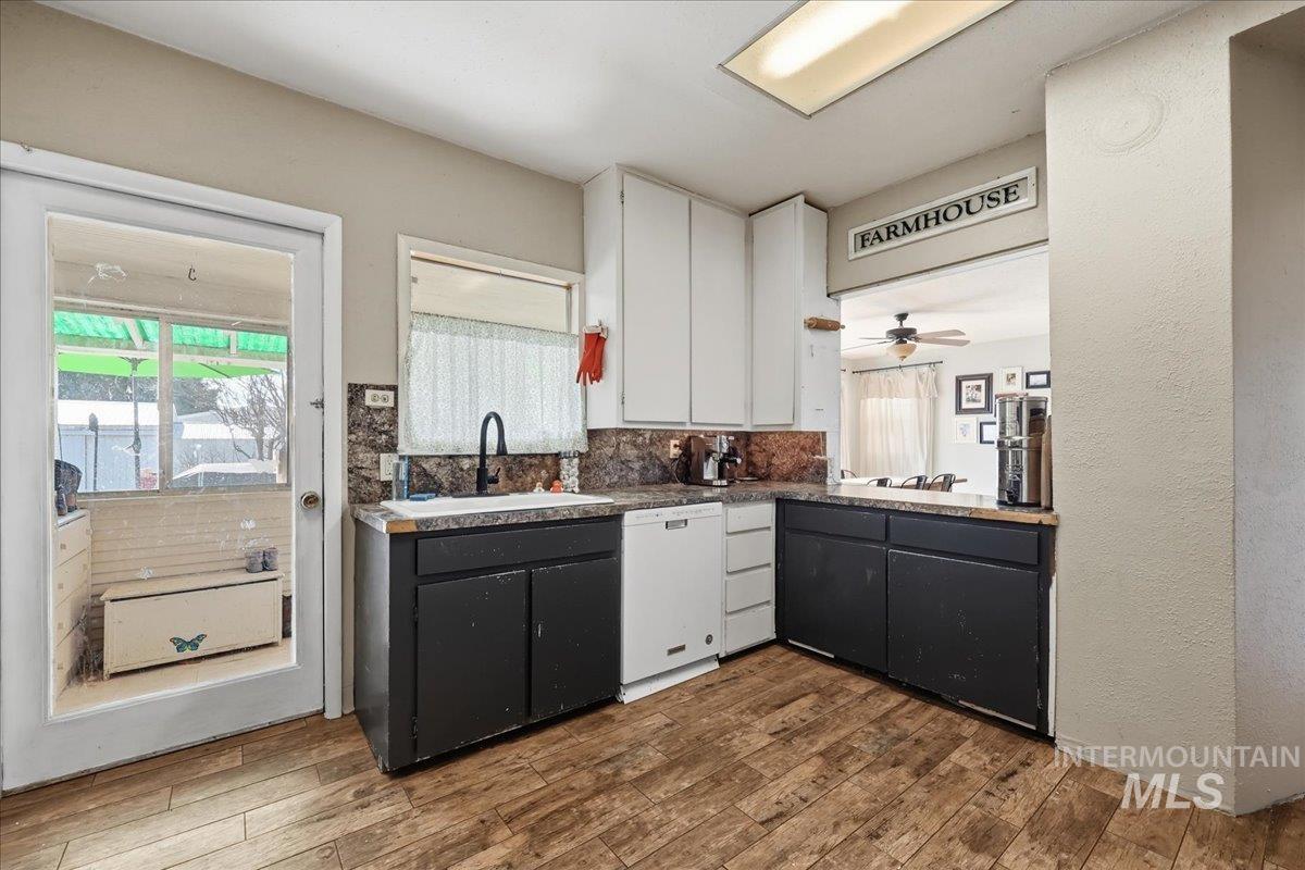 148 Glascock Road Weiser, ID 83672 - Photo 19 of 32 Two tone kitchen featuring white dishwasher, ceiling fan, dark wood-style floors, backsplash, and a textured wall