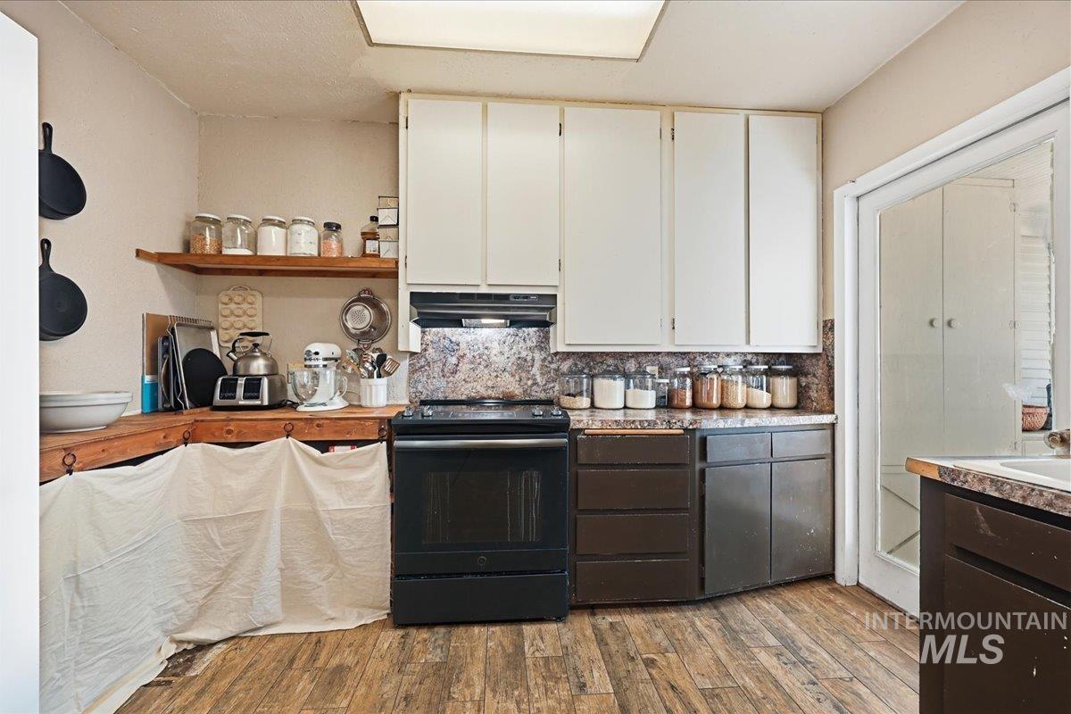 148 Glascock Road Weiser, ID 83672 - Photo 21 of 32 Two tone kitchen featuring two tone cabinets, black range with electric stovetop, open shelves, dark wood-type flooring, and light countertops