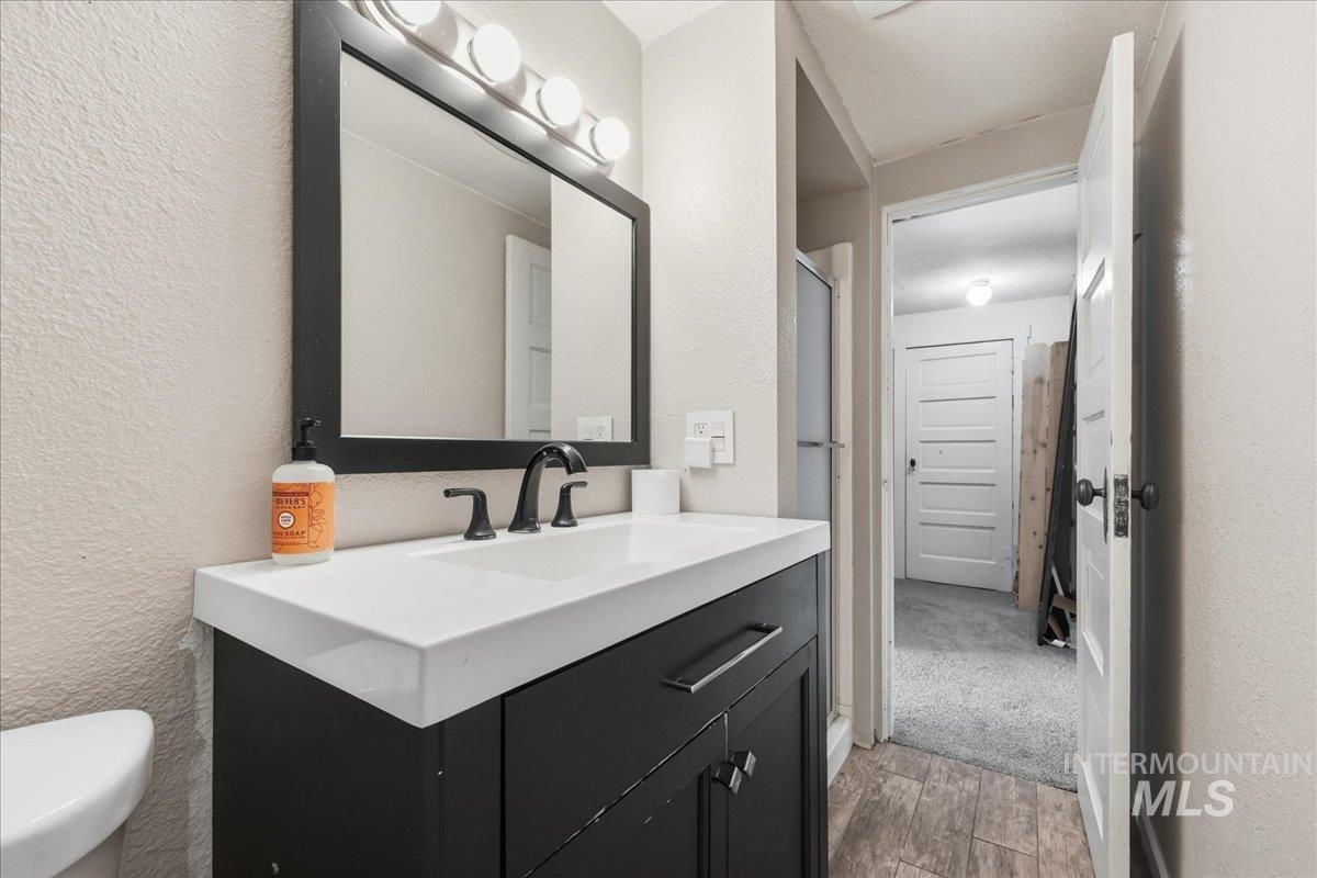 148 Glascock Road Weiser, ID 83672 - Photo 25 of 32 Full bathroom featuring a textured wall, vanity, light wood finished floors, and a shower stall