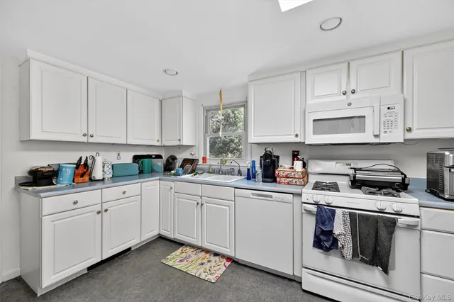 a kitchen with granite countertop white cabinets and white appliances