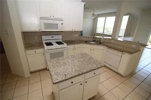 a kitchen with granite countertop a sink stove and cabinets