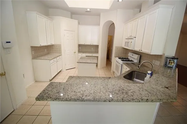 a kitchen with granite countertop a sink a stove and cabinets