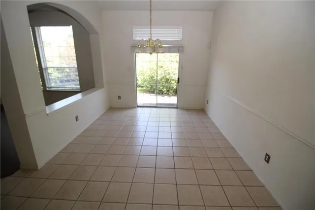 a dining hall with a stove a faucet a chandelier and kitchen view