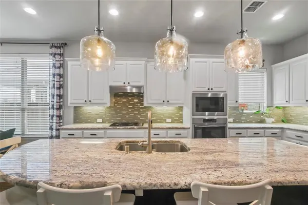 a kitchen with stainless steel appliances kitchen island granite countertop a stove and a sink