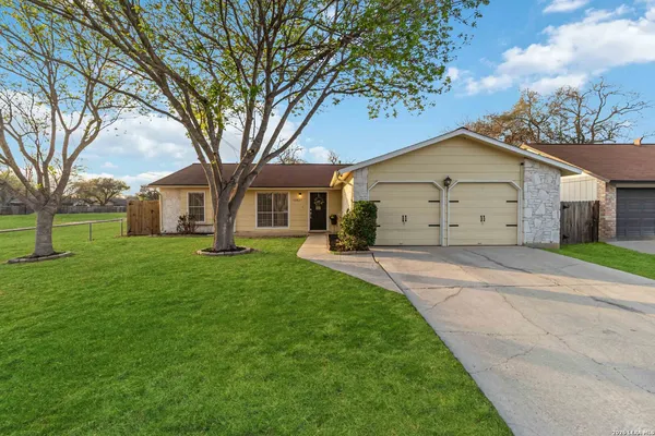 a view of a white house with a big yard and large trees