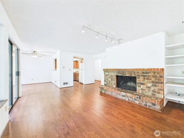 a view of empty room with wooden floor and fireplace