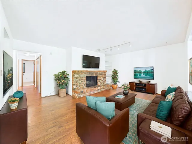 a living room with furniture a fireplace a flat screen tv and a window