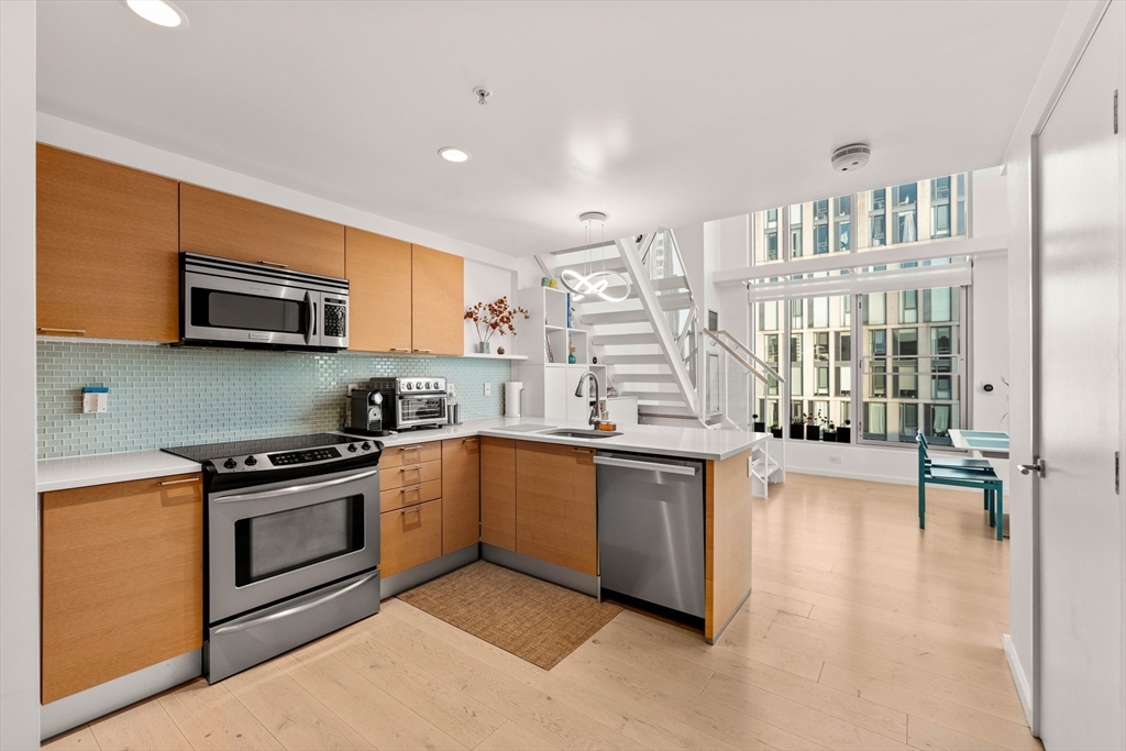 1 Earhart Street, Unit 705 Cambridge, MA 02141 - Photo 8 of 38 a kitchen with stainless steel appliances granite countertop a stove a sink and a microwave