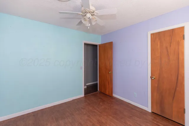 an empty room with windows and fan