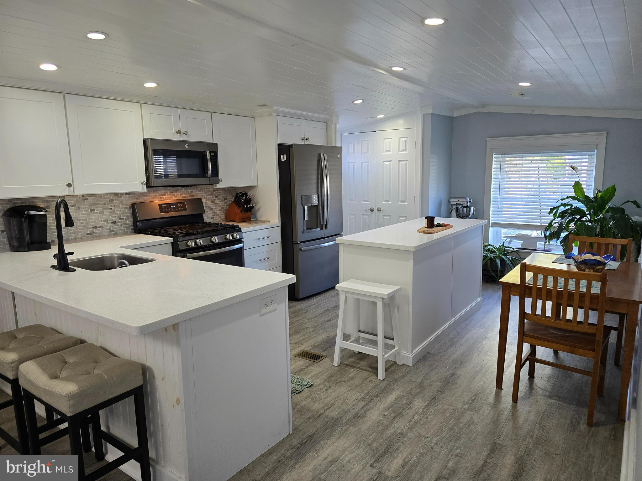 33500 Clover Street Lewes, DE 19958 - Photo 11 of 39 a kitchen with a dining table chairs refrigerator and microwave