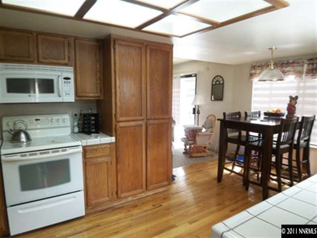 5370 Mountcrest Lane Reno, NV 89523 - Photo 6 of 10 a kitchen with stainless steel appliances granite countertop a stove a refrigerator a dining table and chairs with wooden floor