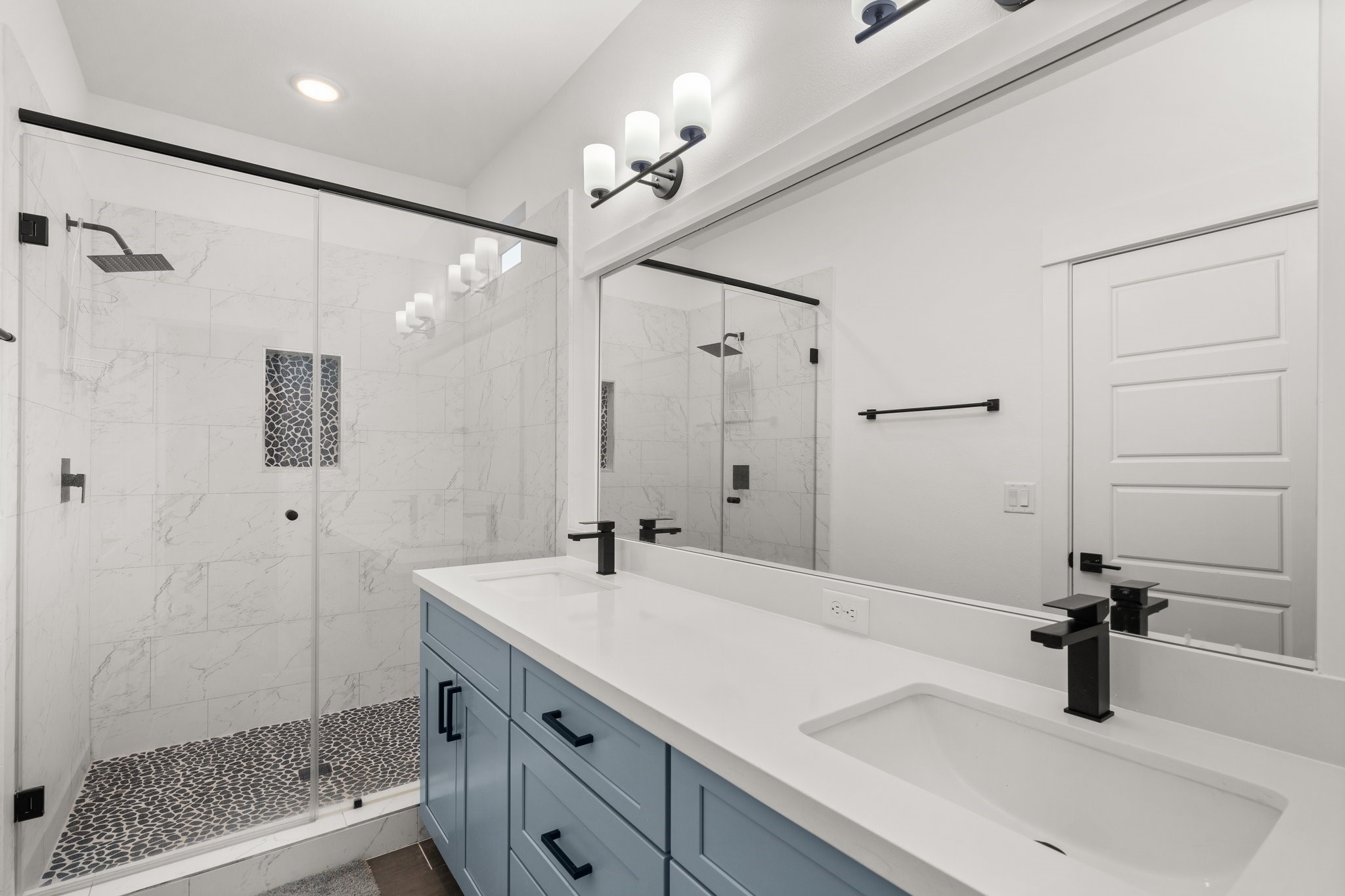 2928 Stevens Street Houston, TX 77026 - Photo 14 of 30 This modern bathroom features a spacious glass-enclosed shower with elegant tilework and a rainfall showerhead. The double vanity with sleek black fixtures and a large mirror enhances the contemporary feel.