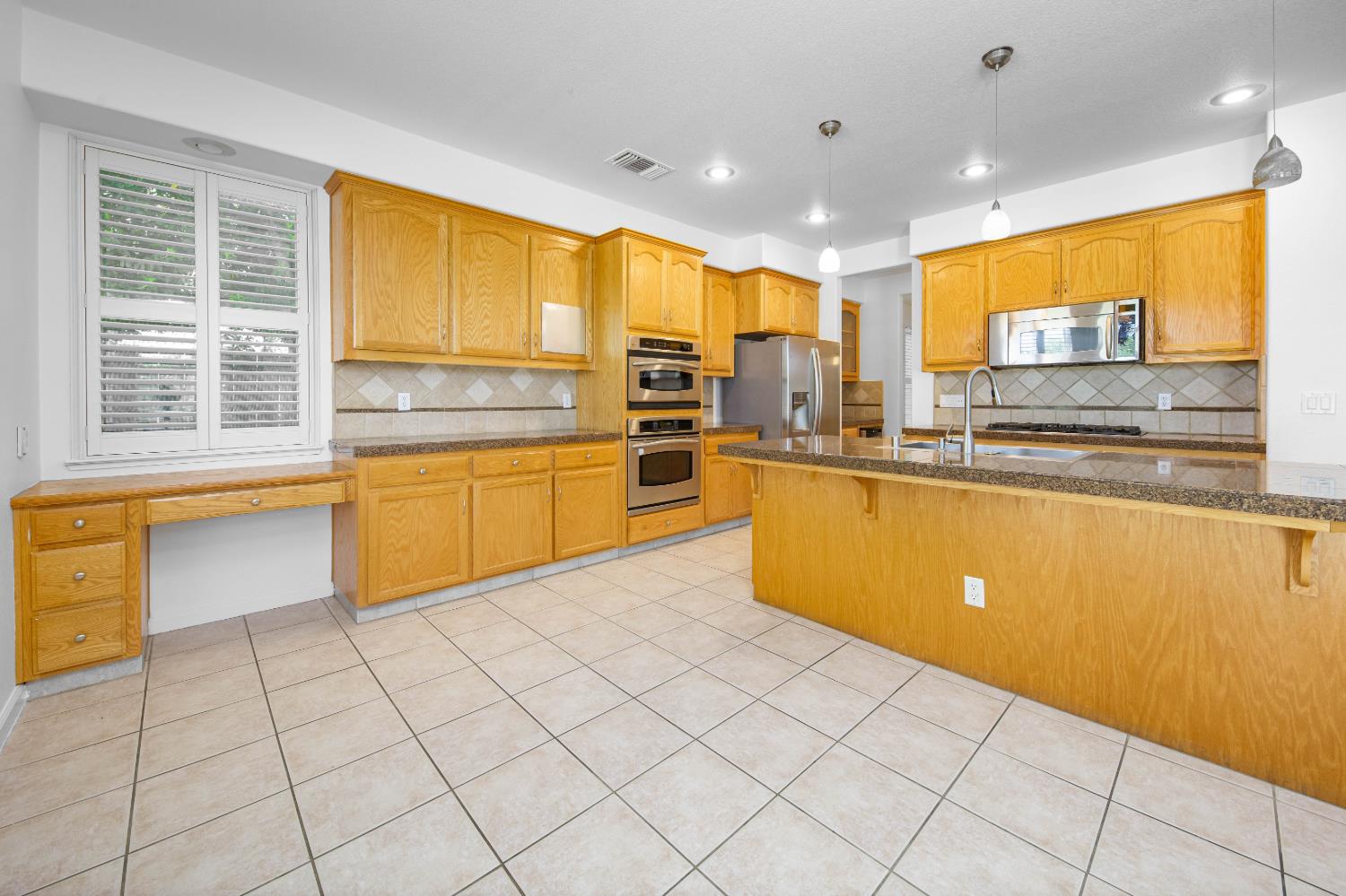 1705 Avignon Lane Modesto, CA 95356 - Photo 22 of 87 kitchen with a kitchen breakfast bar, pendant lighting, light tile patterned floors, dark stone counters, and stainless steel appliances