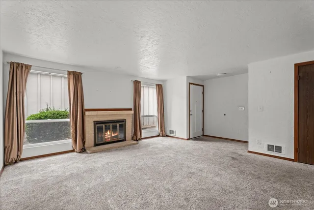 an empty room with windows and fireplace