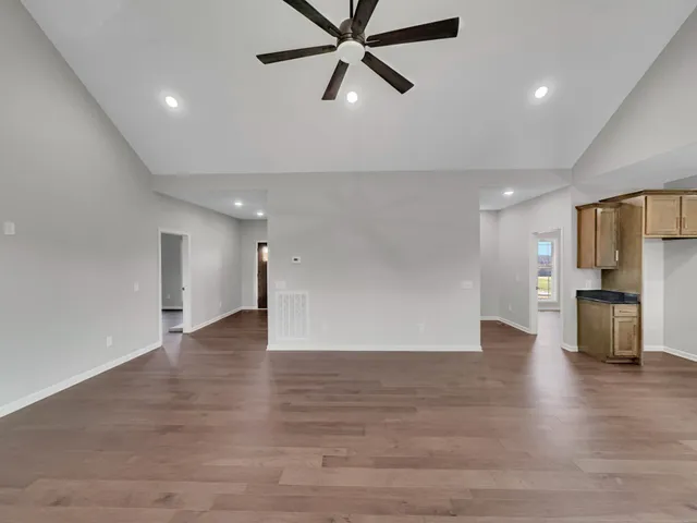 a view of empty room with wooden floor and a ceiling fan