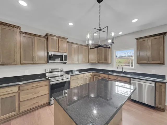 a modern kitchen with stainless steel appliances granite countertop a sink a stove and cabinets