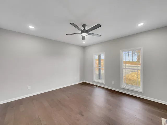 an empty room with wooden floor and windows