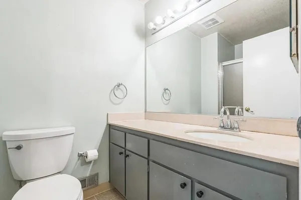 a bathroom with a granite countertop toilet sink and mirror