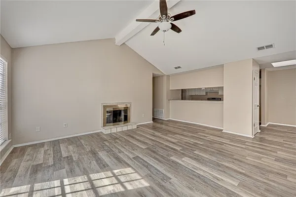 a view of a livingroom with wooden floor and kitchen space with a fireplace
