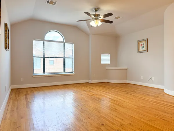a view of an empty room with a window and wooden floor