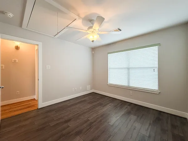 an empty room with wooden floor fan and windows