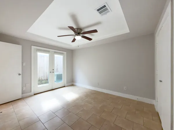 an empty room with chandelier fan and windows