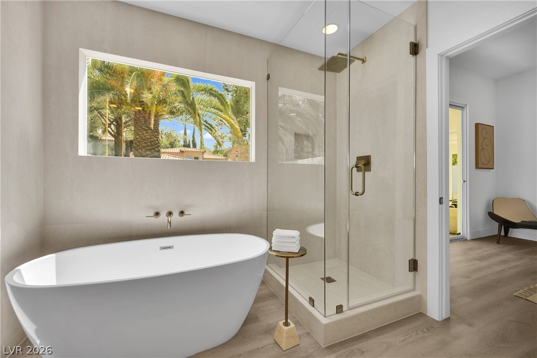 8981 Rivers Edge Drive Las Vegas, NV 89117 - Photo 39 of 69 Indulge in a tranquil retreat with a freestanding soaking tub and a spacious glass-enclosed shower, featuring a captivating view of palm trees.