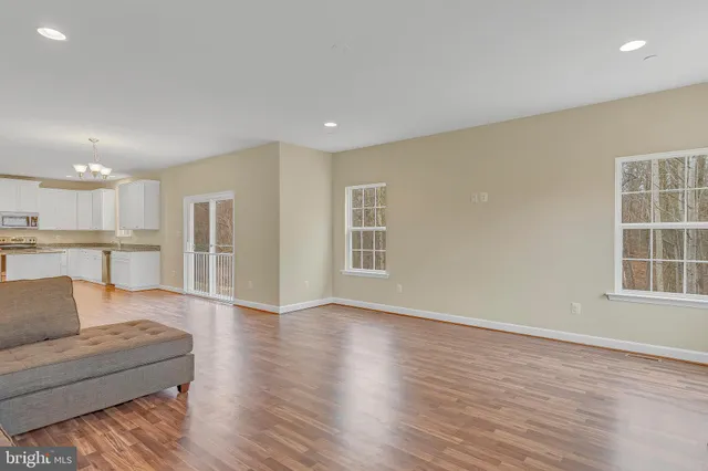 a living room with furniture and a kitchen view with wooden floor