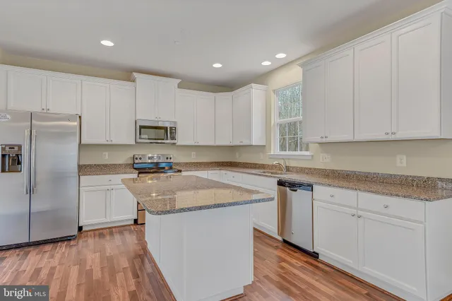 a kitchen with granite countertop white cabinets and stainless steel appliances