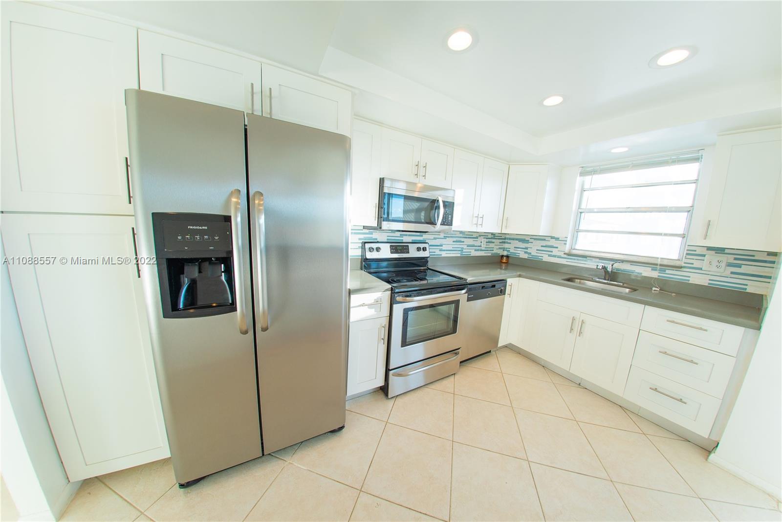 a kitchen with white cabinets stainless steel appliances and a window