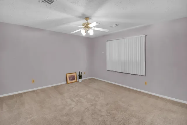an empty room with windows and fan