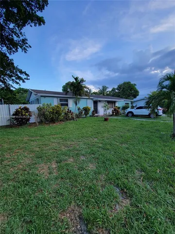 a view of a house with a big yard and large trees