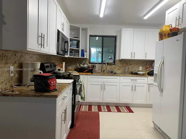 a kitchen with stainless steel appliances granite countertop a refrigerator and a stove