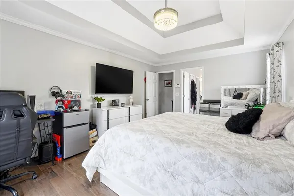 a bed room with a bed a flat tv screen and a dresser