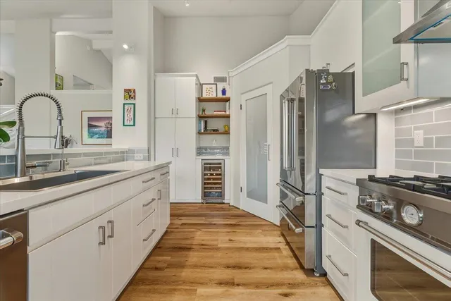 a large kitchen with granite countertop a refrigerator oven a sink and dishwasher with wooden floor