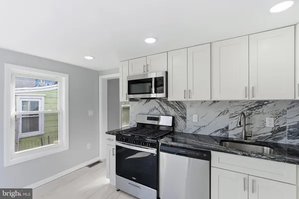 a kitchen with granite countertop white cabinets and stainless steel appliances