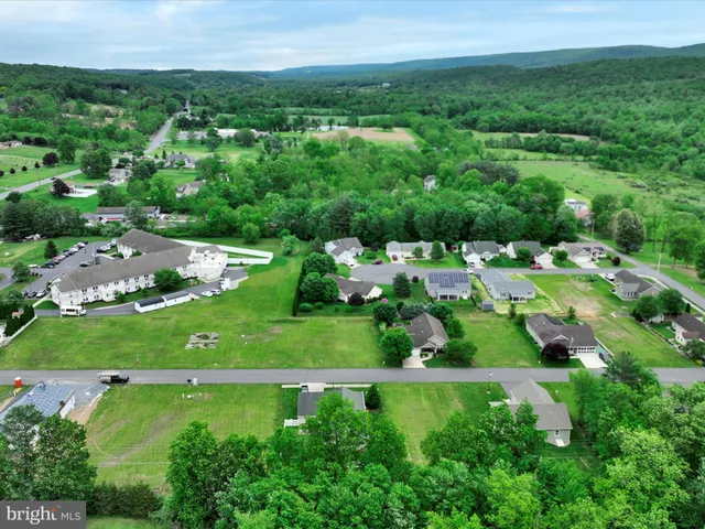 an aerial view of residential houses with outdoor space and trees all around