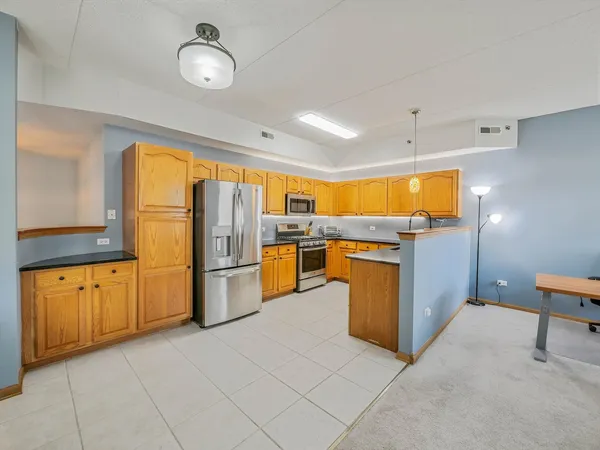 a kitchen with stainless steel appliances granite countertop a refrigerator a oven a sink with island and chairs