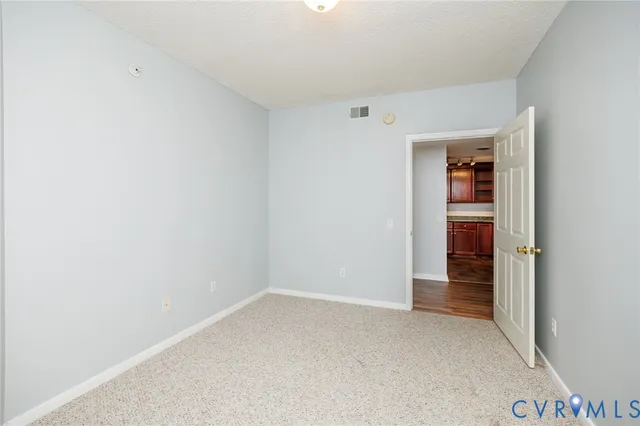 a view of an empty room with closet and wooden door