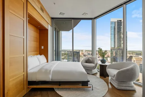 a bedroom with a bed and a large window with outer view