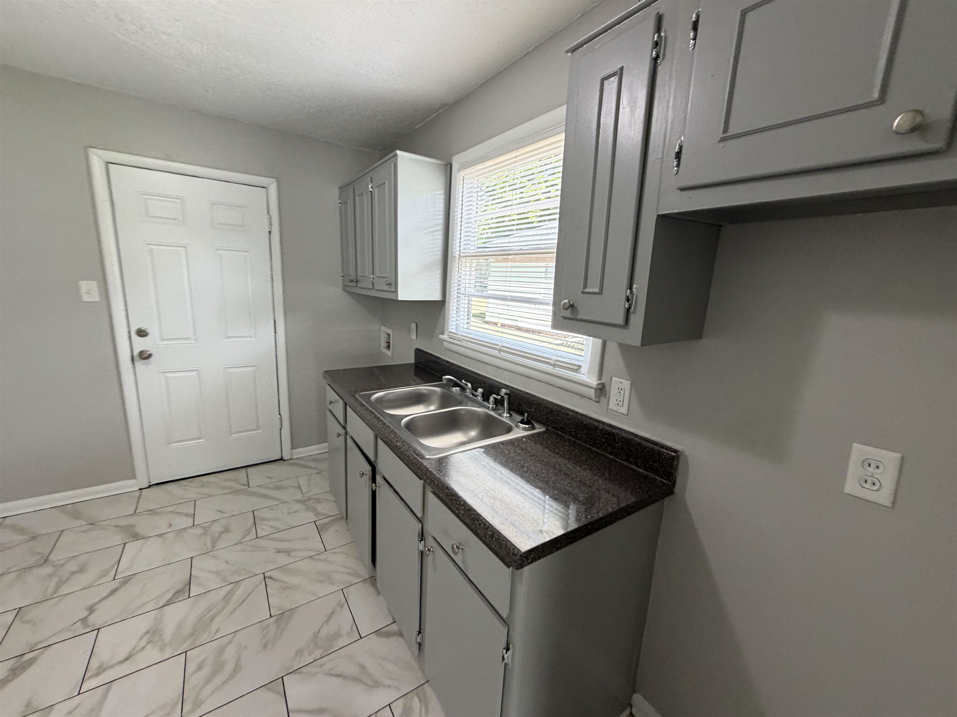 3525 Rochester Road Memphis, TN 38109 - Photo 4 of 10 Kitchen featuring a double stainless steel sink, dark granite-style countertops, and light gray cabinetry
