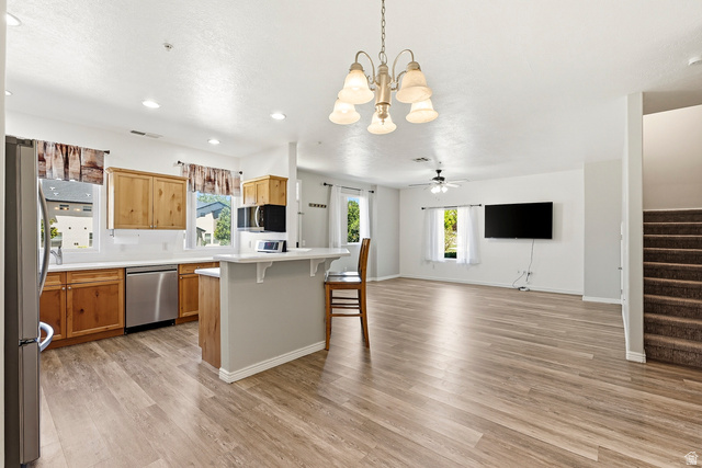 1177 Northfield Road, Unit 26 Cedar City, UT 84721 - Photo 10 of 45 Open-concept living area featuring wood-finish flooring, a kitchen island with seating, stainless steel appliances, and natural wood cabinetry