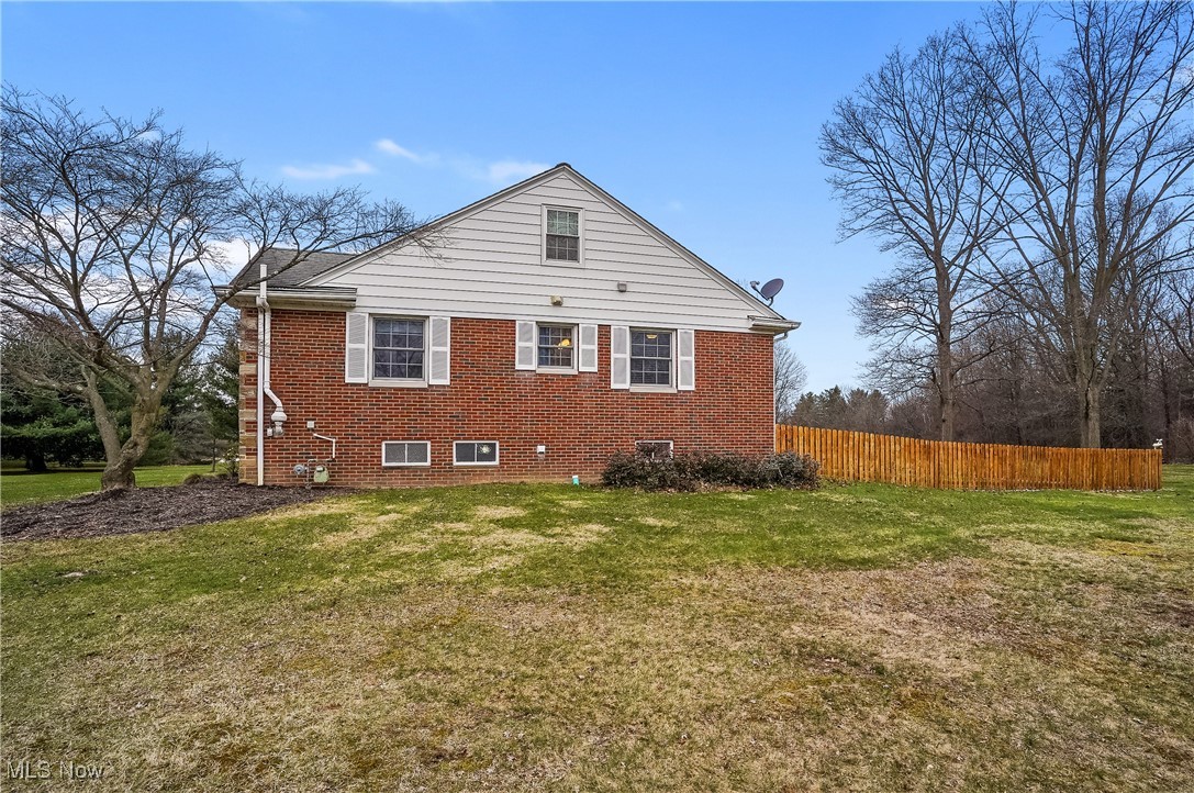 33825 Cannon Road Solon, OH 44139 - Photo 3 of 44 View of side of home featuring a lawn, fence, and brick siding
