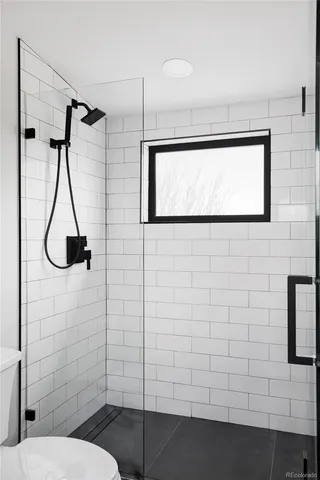 a bathroom with a shower toilet and a window