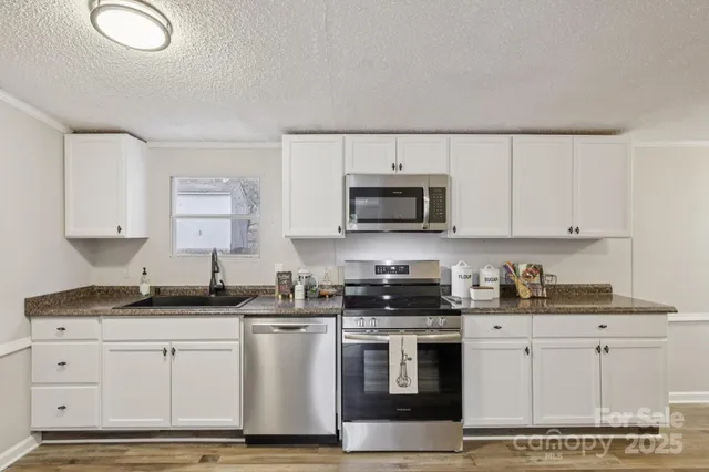 a kitchen with granite countertop white cabinets and stainless steel appliances