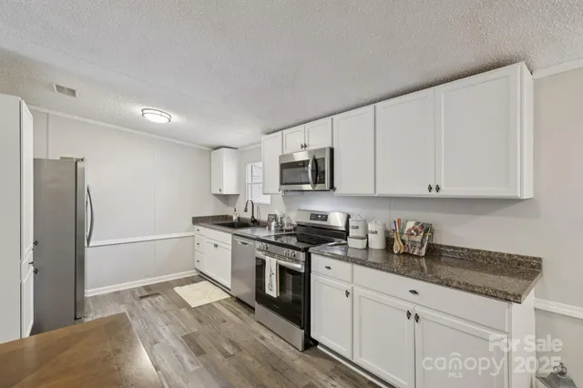a kitchen with stainless steel appliances granite countertop a stove a sink and a refrigerator