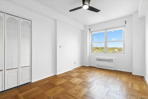 a view of an empty room with window and wooden floor