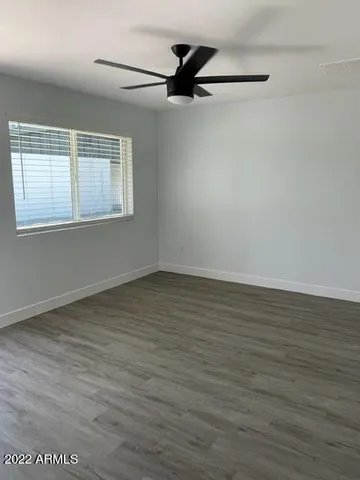 an empty room with wooden floor and a ceiling fan