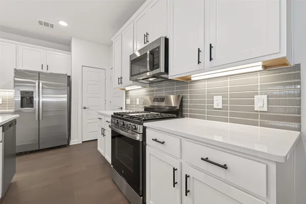 a kitchen with stainless steel appliances granite countertop a stove a refrigerator and a microwave